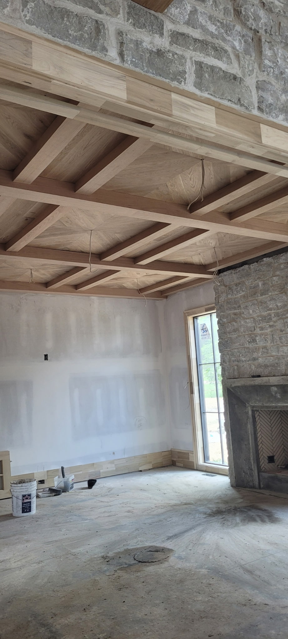 Coffered wood ceiling and stone fireplace during construction